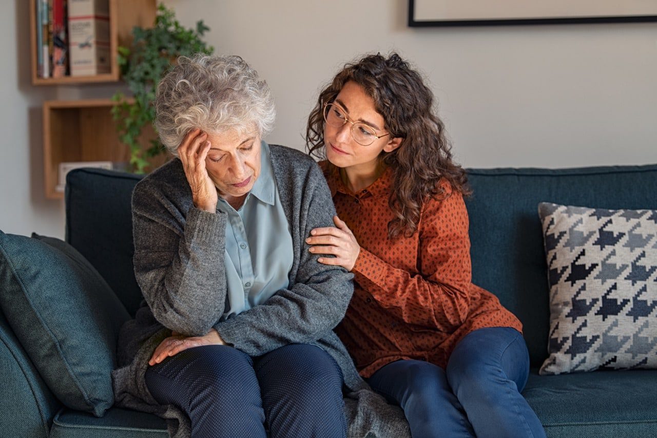 A young woman showing support to her elderly loved one who has depression