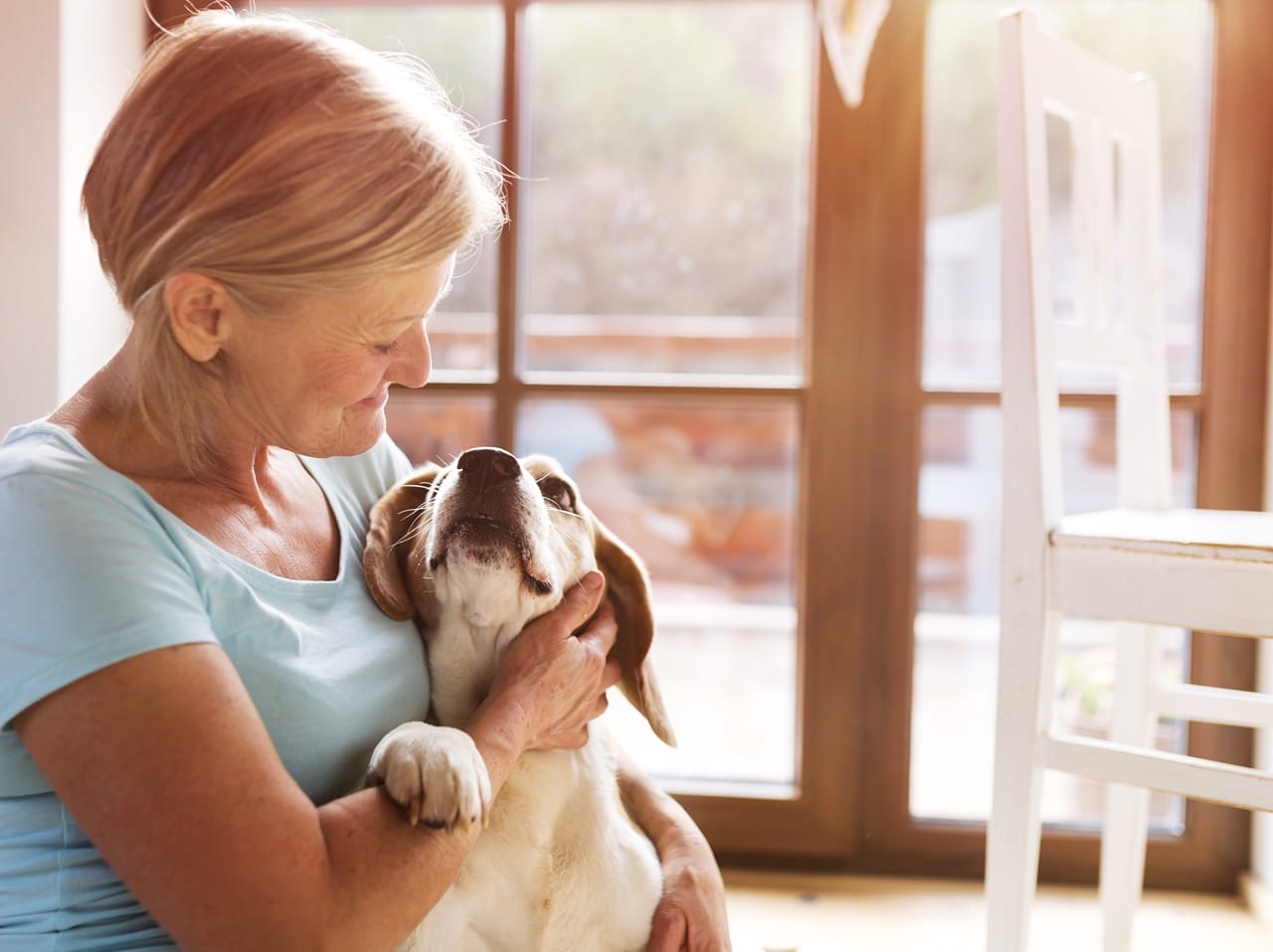 An elderly woman cuddling a dog