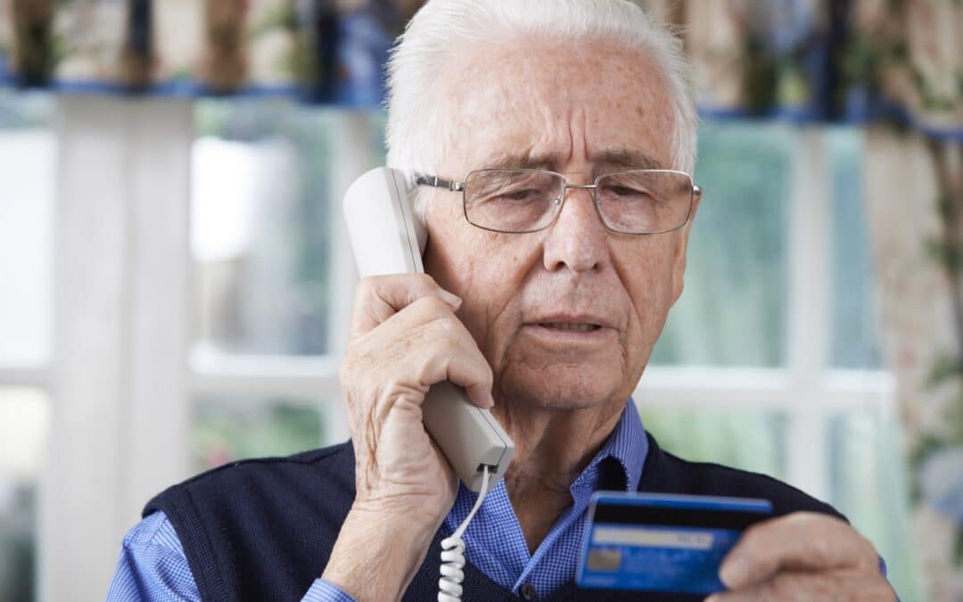 an old man reading his card details to the person he is talking to on the phone