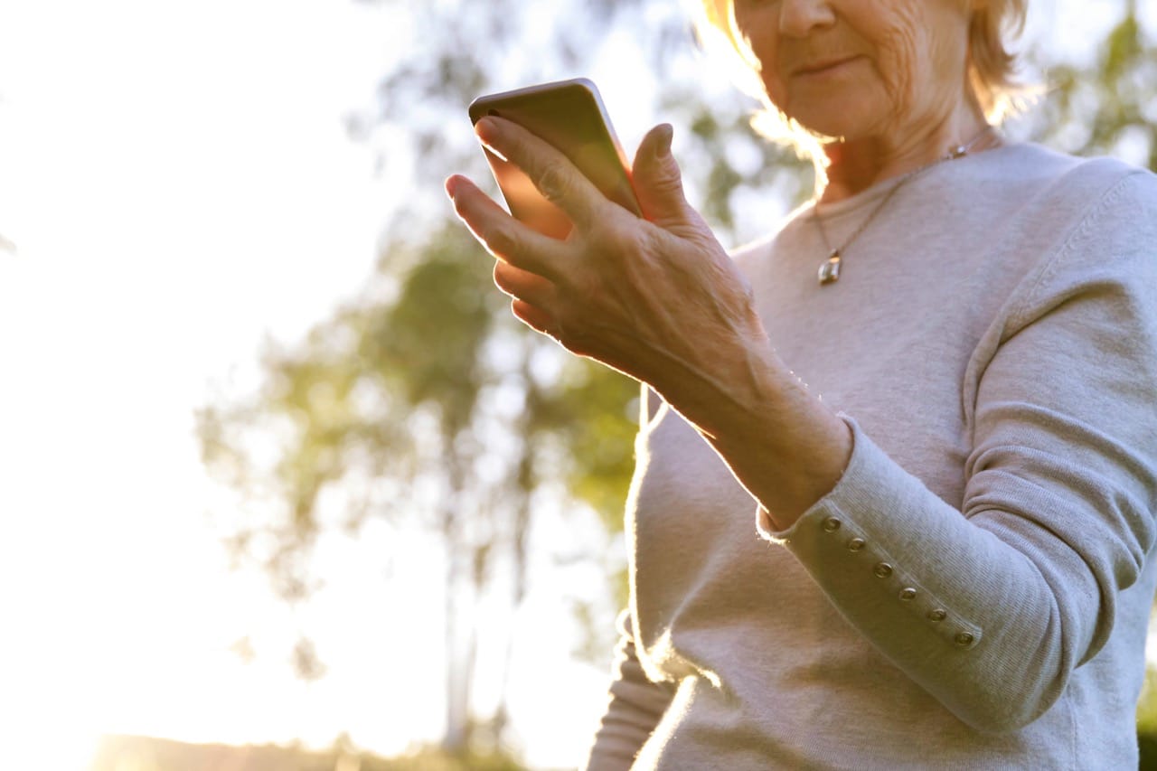 an elderly woman reading a scam message on her phone