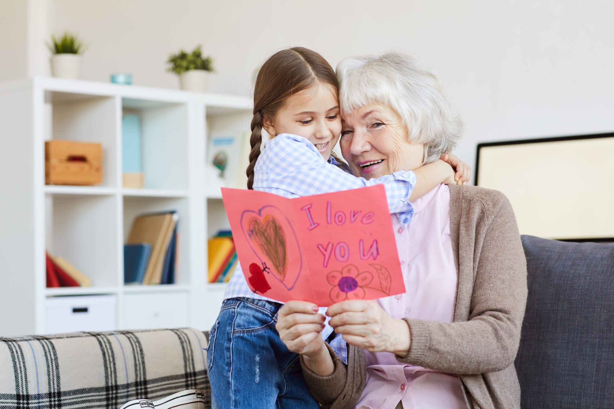 An elderly woman receiving a Valentine's Day card from her granddaughter.