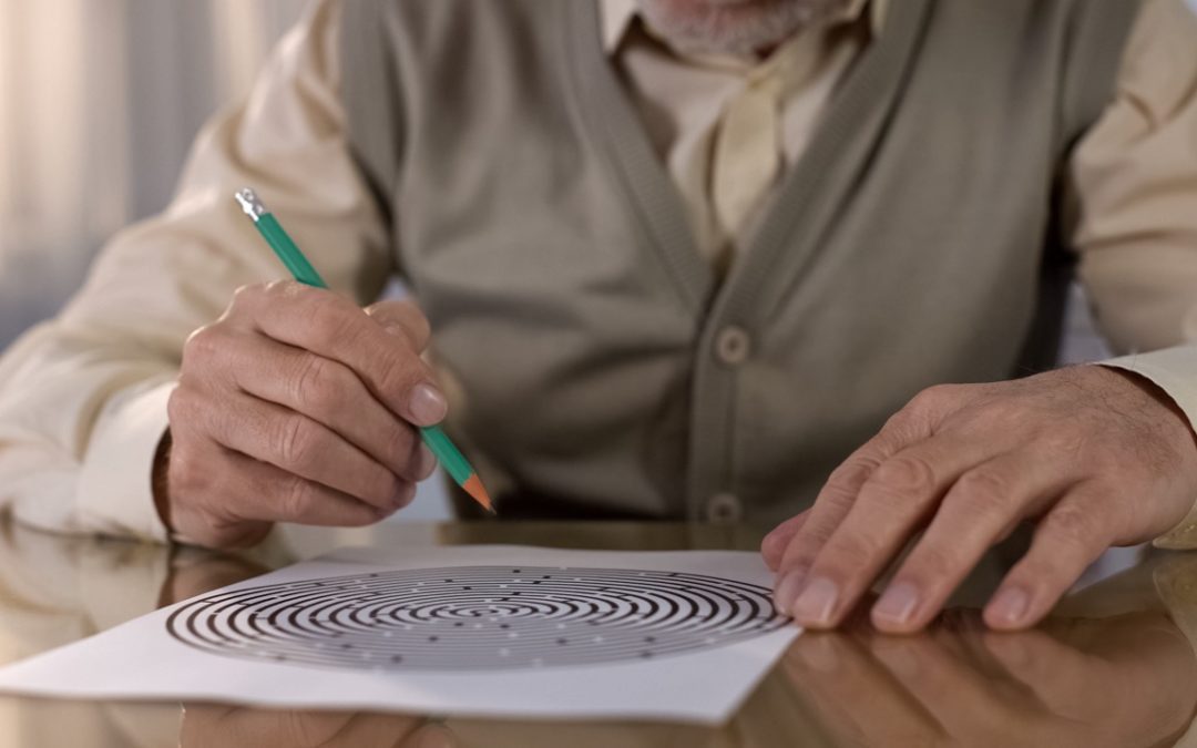 Concentrated retired man solving logic test at table, memory exercise