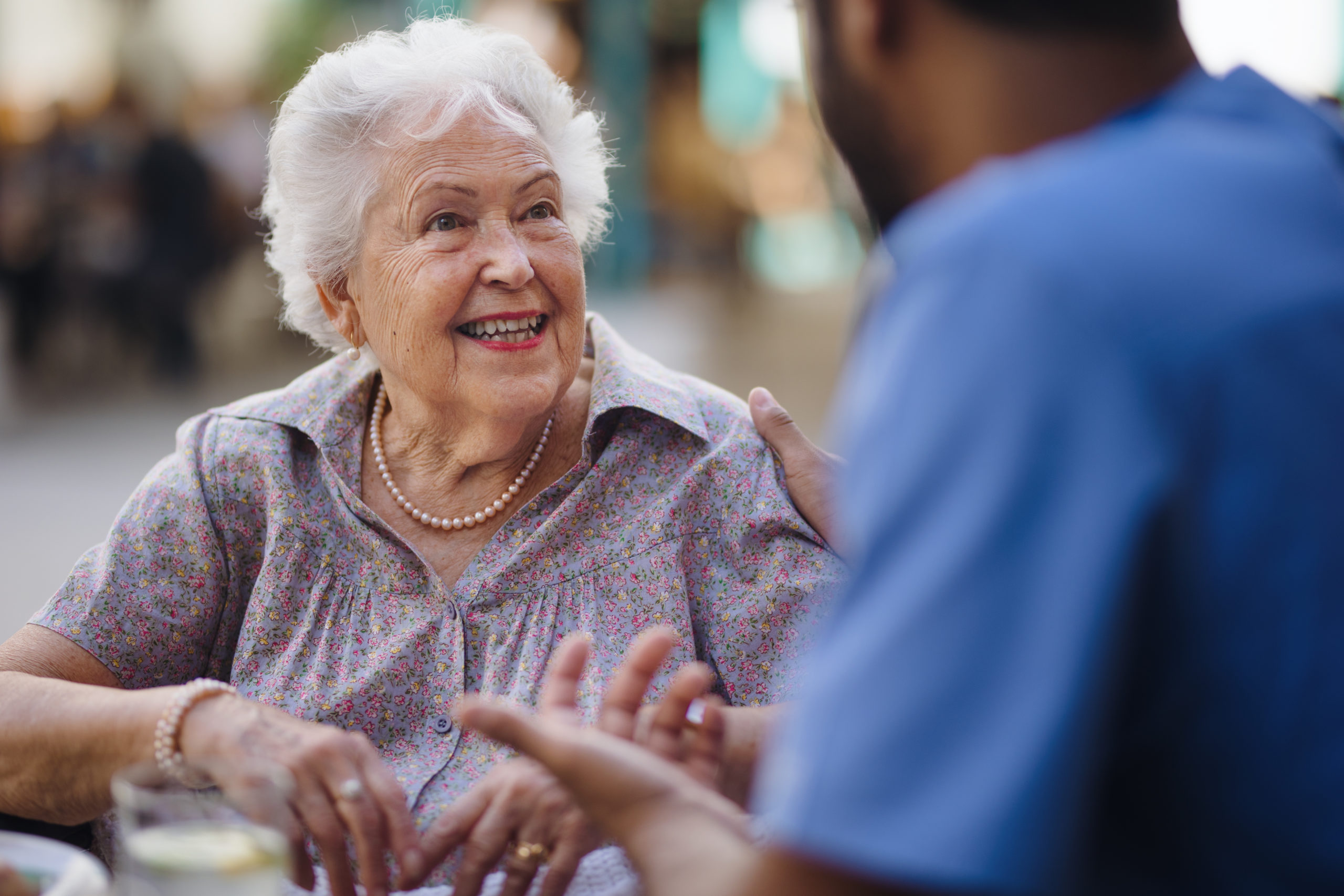 An elderly woman talking to a caregiver