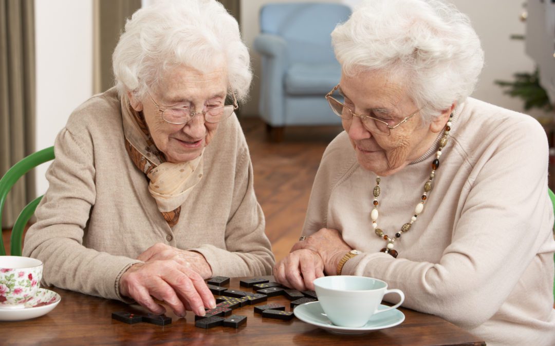 Two elderly women playing with dominoes in an independent living facility