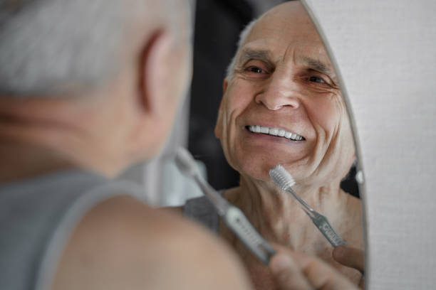 Smiling old man brushing his teeth 